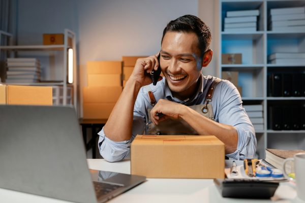 A business owner sells products on websites and online platforms. He is on the phone with a customer A business owner sells products on websites and online platforms. He is on the phone with a customer